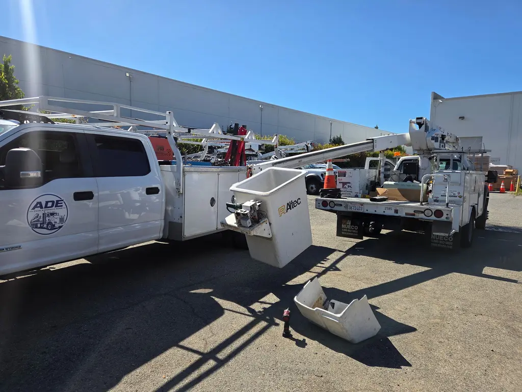 Altec bucket truck with the boom extended and the bucket off for repair next to an ADE service truck