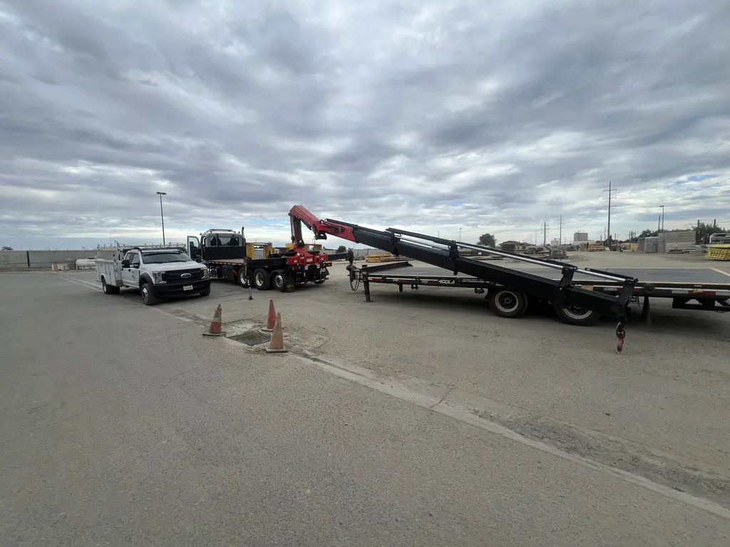 Knuckle boom crane extended over a flatbed trailer during a hydraulic repair call