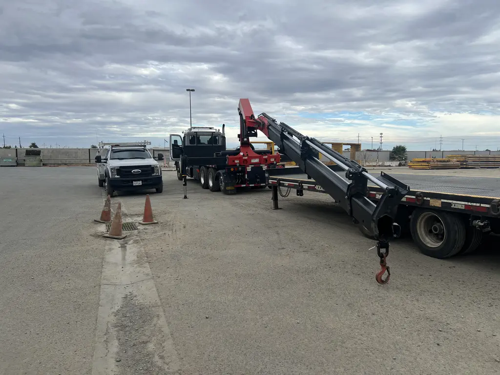 Knuckle boom flatbed trucks lined up in a fleet yard