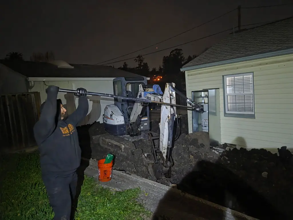 ADE technician working on a mini excavator boom at night