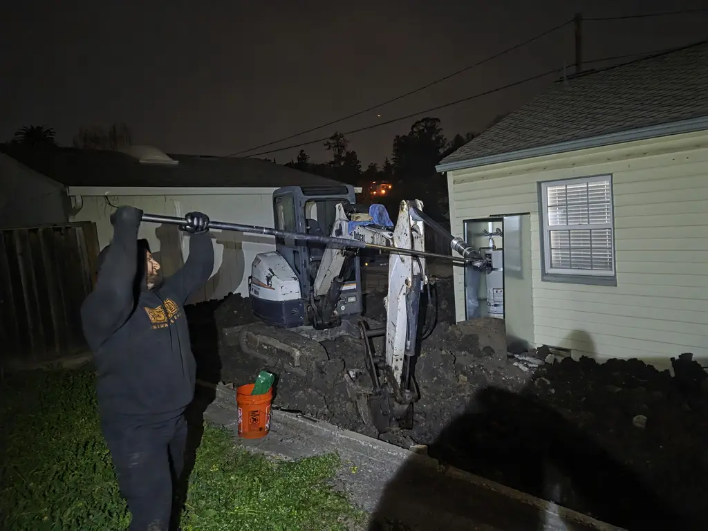 ADE technician working on a mini excavator boom at night