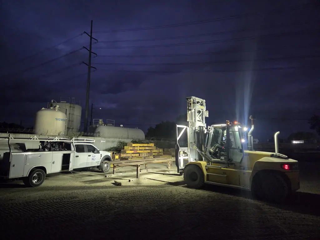 Heavy forklift lit up by an ADE service truck on a night call
