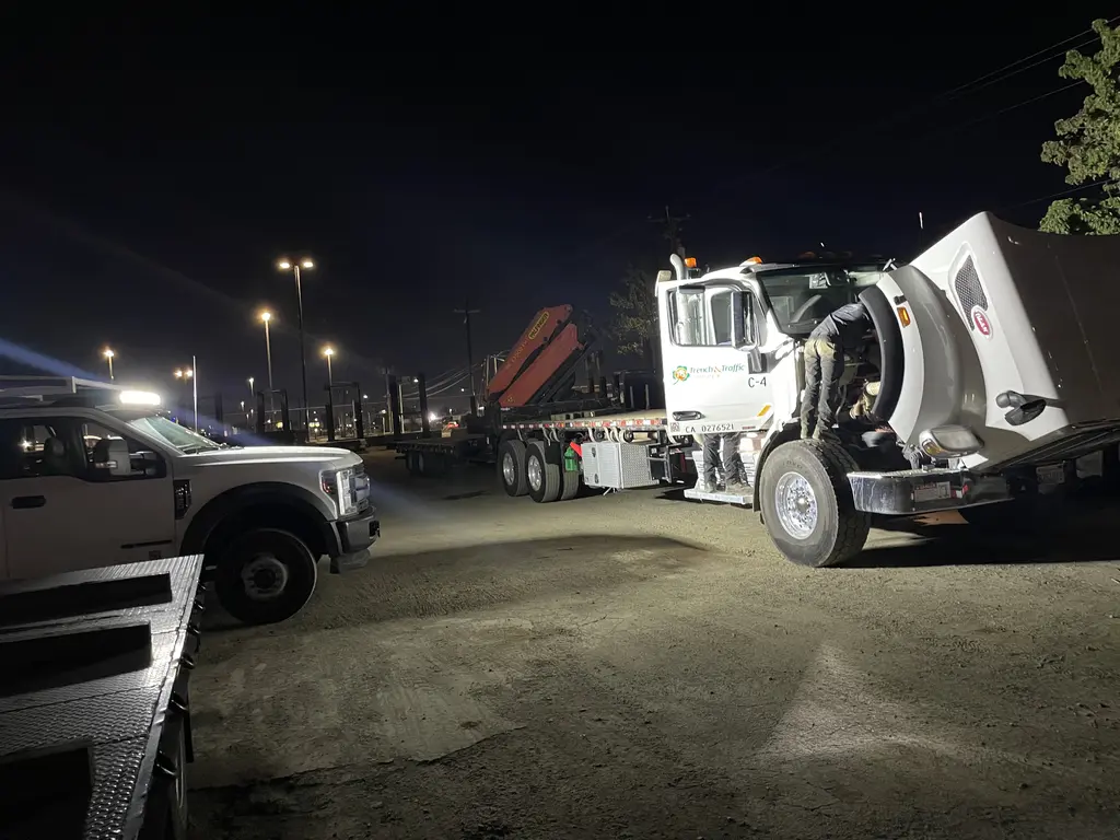 ADE technician working on a semi tractor at night under work lights
