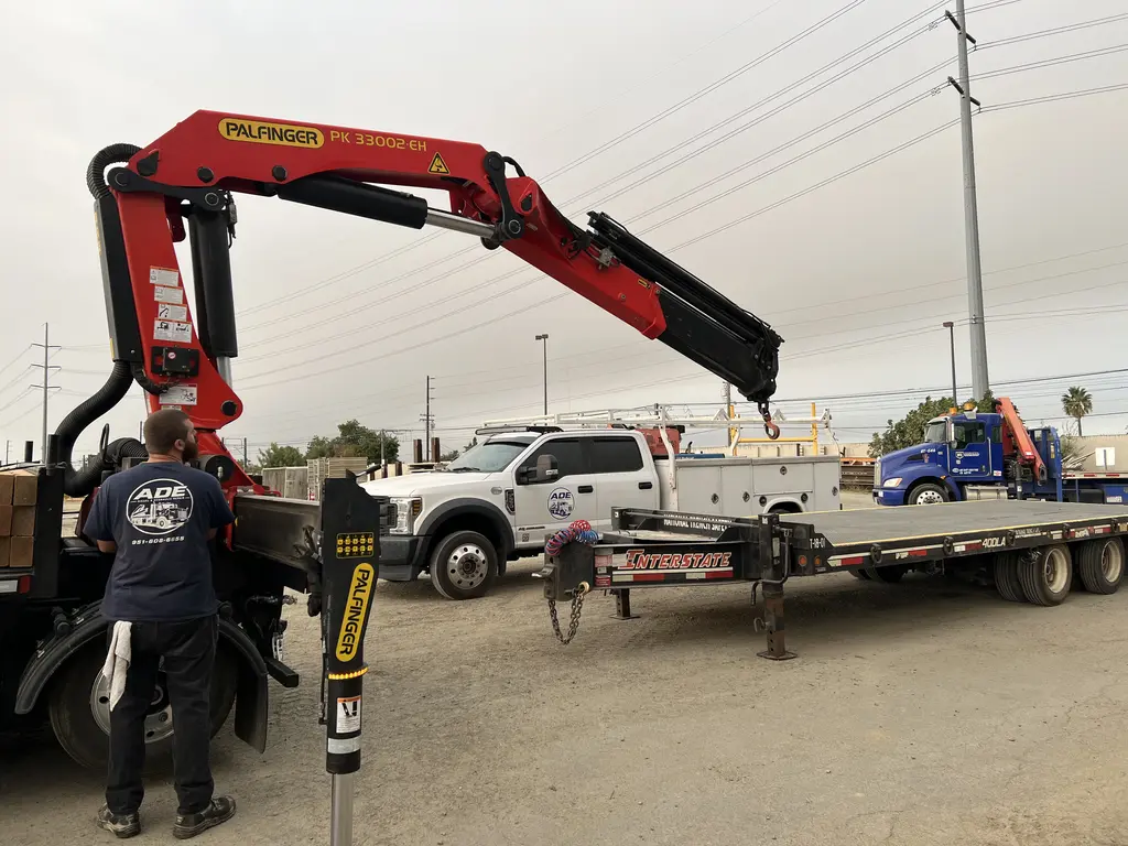 ADE technician working on a Palfinger knuckle boom crane on a flatbed